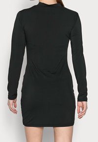 Mustat pitkähihaiset mekko, tiukka malli, sileä pinta, polven pituinen, pyöreällä kauluksella ja kerätty yksityiskohta takana.
