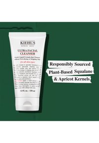 Hvit tube med flip-lock, merket "Kiehl's Ultra Facial Cleanser." Har svart tekst og røde detaljer; fremhever nøkkelingredienser og bruksområder.