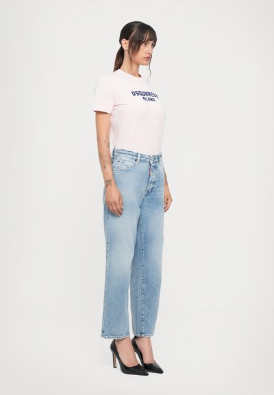 Pink cotton t-shirt with dark blue logo, paired with light blue high-waisted denim jeans. Black pointed toe heels complete the outfit.