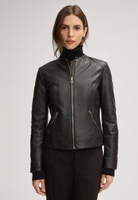 Schwarze Lederjacke mit einer figurschmeichelnden Passform, Reißverschluss auf der Vorderseite, gesteppte Schulterakzente und zwei Reißverschlusstaschen an den Seiten. Strukturiertes Ärmeldesign.