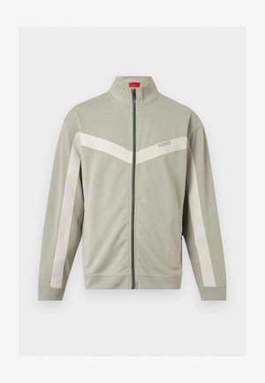 Veste zippée gris clair avec des bandes blanches sur les manches et la poitrine, dotée d'un col montant et du logo Hugo à l'avant.