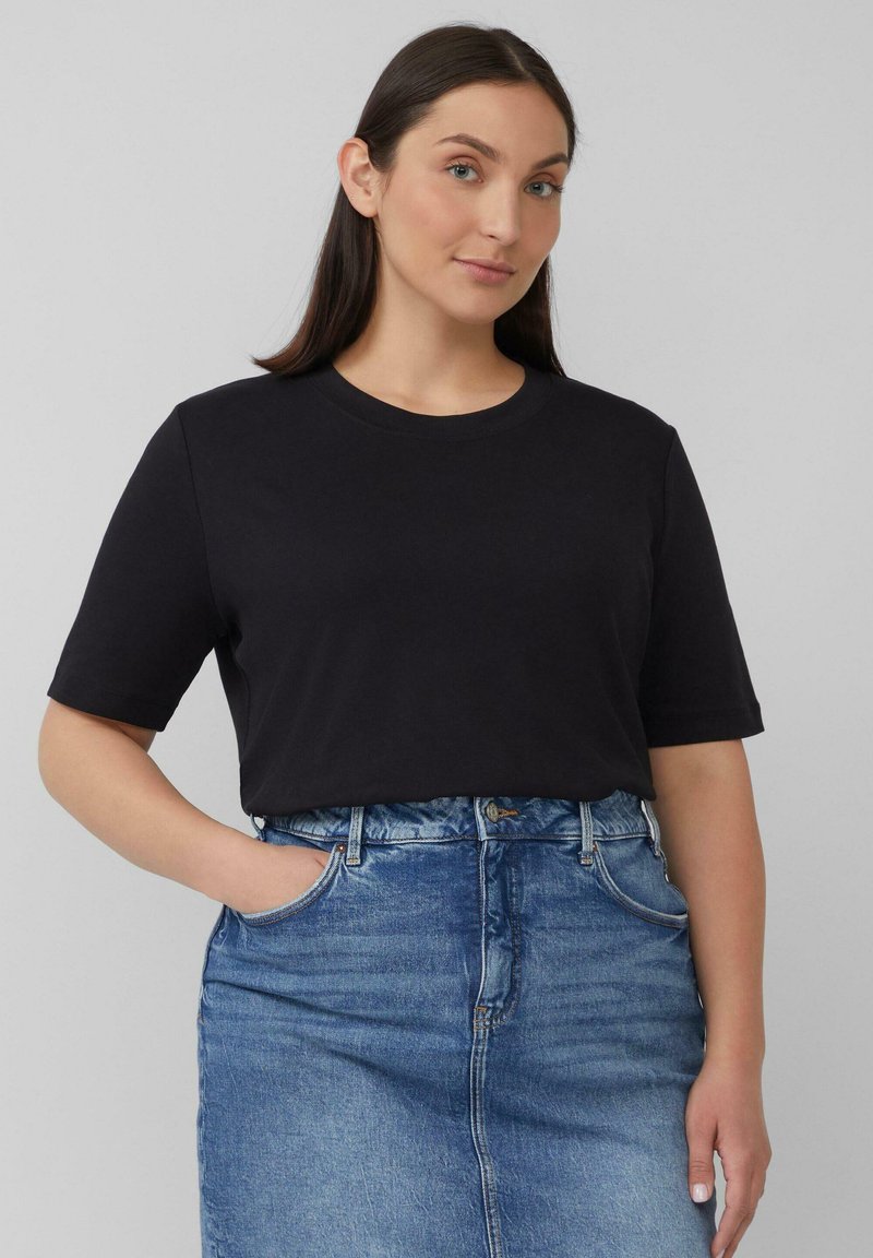 Schwarzes Baumwoll-T-Shirt mit kurzen Ärmeln und rundem Ausschnitt, kombiniert mit einem taillierten Jeansrock in heller Waschung. Glatte Textur und lässiges Design.