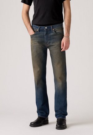 Faded blue denim jeans with a straight cut, featuring a button fly, five pockets, and subtle whiskering near the knees.
