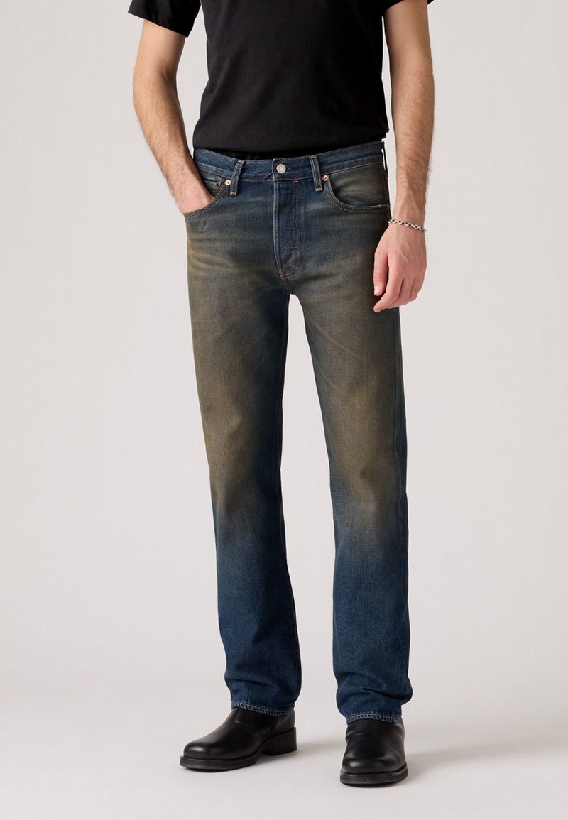 Faded blue denim jeans with a straight cut, featuring a button fly, five pockets, and subtle whiskering near the knees.