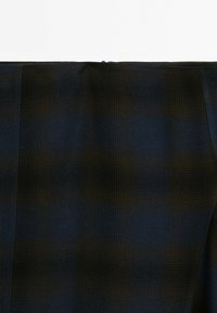 Tissu bleu foncé avec un motif à carreaux subtil dans des nuances variées. Texture lisse, finition légèrement brillante. Comprend une fermeture éclair dissimulée en haut.