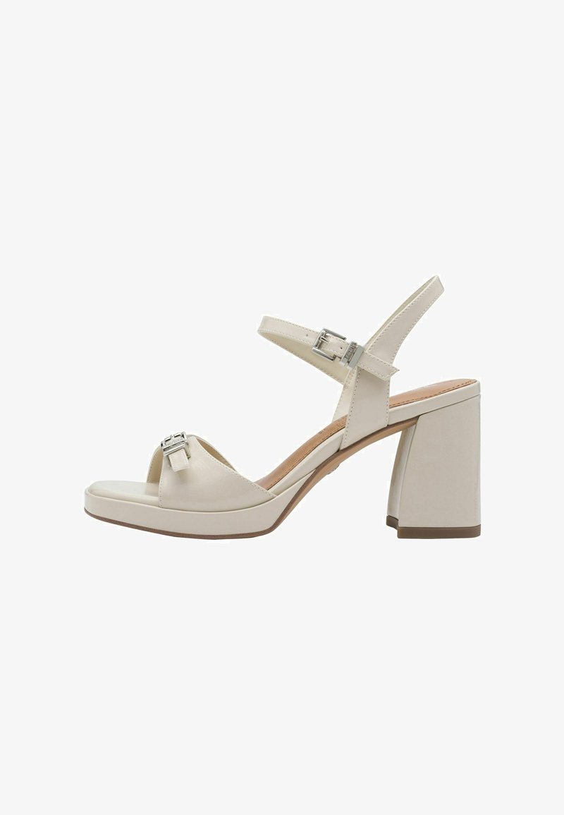 Sandales à talons hauts beiges avec un talon bloc épais. Elles présentent un bout ouvert, deux sangles ajustables et une boucle en accent. Fini lisse.