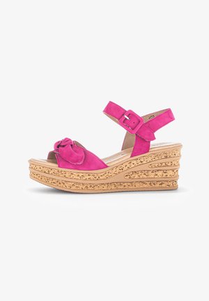 Sandal con zeppa in suede fucsia con dettaglio a fiocco, cinturino alla caviglia regolabile e tacco effetto sughero. Design open toe e soletta imbottita.