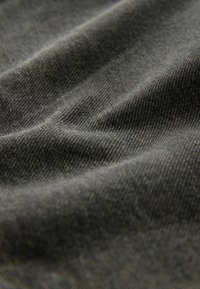 Mørkegrå denimstof med en blød, struktureret overflade og subtile linjer og folder, der indikerer fleksibilitet og dybde i materialet.