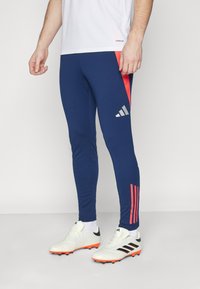 Marineblå træningsleggings med et rødt accentpanel og sølvlogo. Tætsiddende design med kontrasterende striber ned ad siderne. Tekstureret stof.
