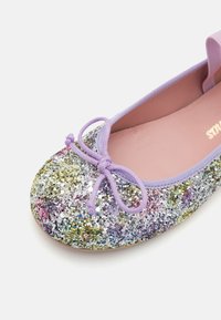 Ballet flat glitterato con paillettes multicolori, bordatura elastica viola e un dettaglio a fiocco sulla punta. Soletta rosa liscia, forma arrotondata.