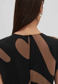 Schwarzes Oberteil mit einem beigen abstrakten Muster, Rundhals-Ausschnitt, Knopfverschluss im Rücken und glatter Textur.