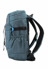 Mochila de tela azul con correas acolchadas, tapa con cremallera, bolsillo de malla en el lateral y hebilla ajustable. Presenta una superficie texturizada y costuras reforzadas.