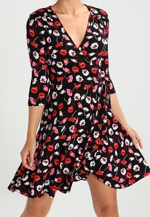 Robe portefeuille florale en tissu noir, ornée de fleurs rouges, roses et blanches. Manches trois-quarts et jupe évasée avec un ourlet froncé.