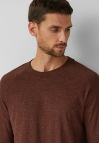 Brauner langärmeliger Sweatshirt mit Rundhalsausschnitt, aus einem strukturierten, gestrickten Stoff gefertigt. Verfügt über Raglanärmel und einen lockeren Schnitt.
