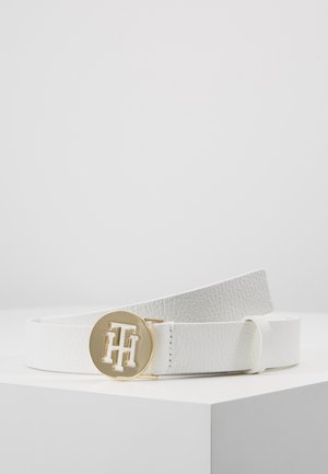 Ceinture en cuir blanc texturé avec une boucle ronde en or ornée des initiales embossées "TH", présentée sur une surface blanche sur un fond uni.