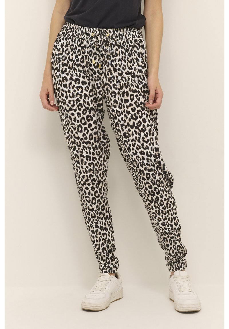 Joggingbroek met luipaardprint van zachte stof, met een elastische tailleband met trekkoord, aansluitende boorden en zijzakken. Witte sneakers te zien.