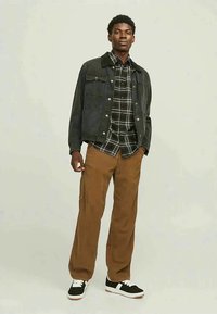 Dark denim jacket with a black collar over a black and white checked shirt, paired with brown corduroy pants and black sneakers.