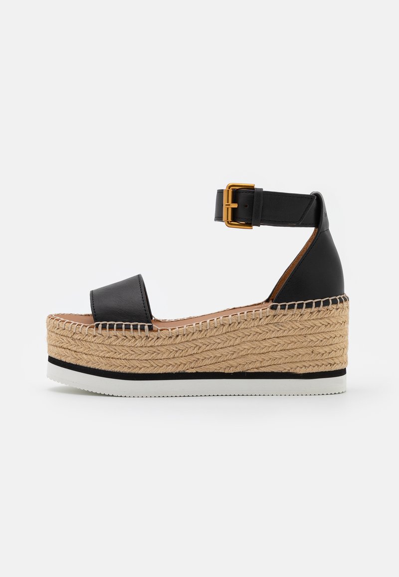 Sorte lærvamp sandal med en jute rebplatform, justerbar ankelrem og en rektangulær spænde. Har en hvid gummisål.