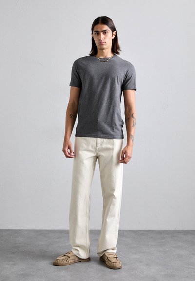 Grå t-skjorte med kort erme, løse hvite bukser og beige slip-on sko. Tilbehøret inkluderer en gullkjede. Enkle og uformelle design.