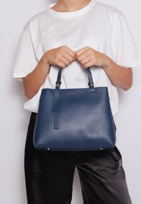 Borsa a mano in pelle blu con finitura texturizzata e due manici corti, dotata di hardware color oro e una forma rettangolare elegante.