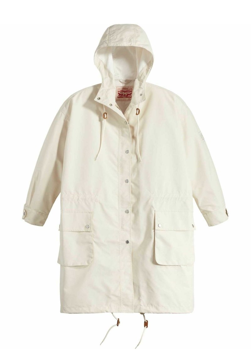 Chaqueta de lluvia ligera de crema con capucha, dos bolsillos frontales, cierres a presión, cintura con cordón y tejido texturizado con un ligero brillo.