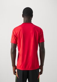 Rode sportieve t-shirt met korte mouwen, ronde hals, gemaakt van glad, lichtgewicht stof, ontworpen voor actieve kleding. Geen zichtbare logo's of patronen.