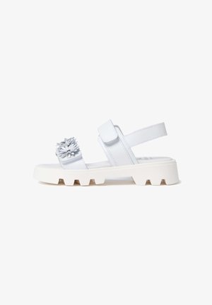 Sandale blanche à semelle épaisse avec des brides ajustables et des ornements floraux décoratifs sur la bride avant, vue de côté.