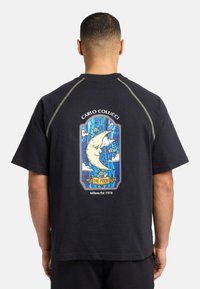 Sort t-shirt med kort ærme, der har et farverigt grafikdesign af månen og skyerne på ryggen, med kontrasterende syninger.