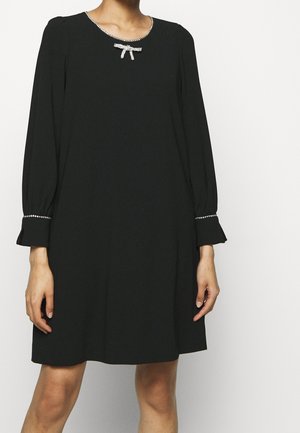 Zwarte jurk met lange mouwen, met een halslijn en manchetten afgewerkt met strass-steentjes, met een klein strass strikdetail aan de kraag.