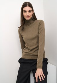 Barna garbó pulóver bordázott textúrával, testhezálló fazonnal és hosszú ujjal, magas derekú fekete nadrággal párosítva.