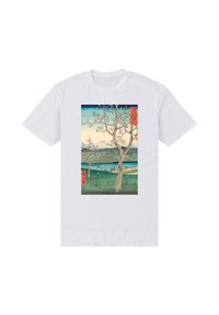 Bílé tričko s potiskem krajinářského motivu v rámečku, zobrazující stromy, řeku a hory v odstínech modré, zelené a růžové s červenými akcenty.