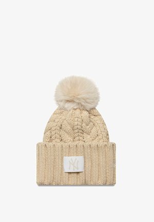 Berretto beige in maglia con un design a trecce testurizzate, risvolto pieghevole e pompon in pelliccia sintetica sulla parte superiore; include una toppa con logo bianco.