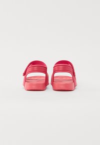 Sandale roz slip-on cu o textură netedă și lucioasă, cu spatele deschis și detaliu ajustabil al curelei. Design ușor, potrivit pentru purtarea zilnică.