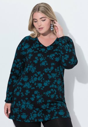Sort langærmet tunika med teal blomsterprint, V-hals design og afslappet pasform, parret med sorte leggings. Glat tekstur.