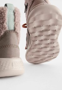 Braune Wildleder-Ankleboots mit plüschartigem Obermaterial und Gummisohle, ausgestattet mit einer hellblauen Ziehlasche und orangefarbenen Akzenten an den Schnürsenkeln.