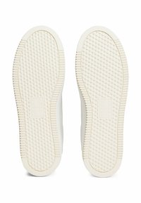 Semelles de sneakers blanches avec un motif texturé, présentant une forme de diamant sur la surface et un logo de marque intégré sur le côté.