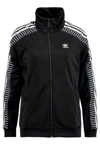 Svart zip-up-jacka gjord av slätt tyg, med vita randiga detaljer på axlarna, hög krage och en Adidas-logotyp på bröstet.