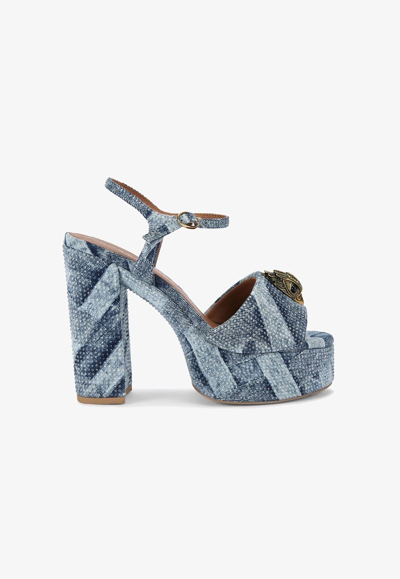Sandali con tacco alto e piattaforma in denim blu con un tacco largo. Caratterizzati da una fibbia circolare e un occhio decorativo a forma di ala sulla parte anteriore.