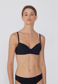 Černá podprsenka s kosticemi, nastavitelnými ramínky, hladkým materiálem a bezšvovým designem. Obsahuje jemný detail uprostřed švu.