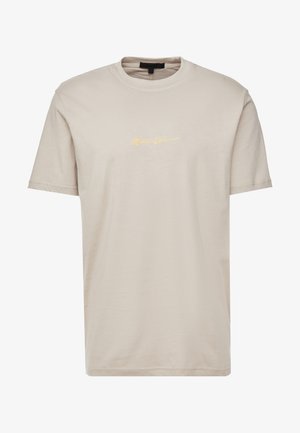Beige katoenen t-shirt met een ronde hals, korte mouwen en een iets losse pasvorm. Heeft een goudkleurig cursief logo aan de voorkant.