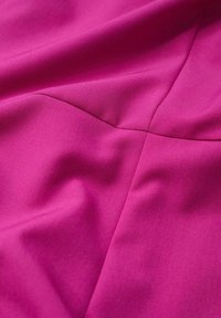 Tissu fuchsia à la texture lisse, présentant des plis subtils et des lignes de couture. Le matériau semble léger avec un léger éclat.