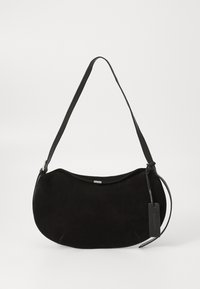 Sac à épaule en daim noir avec une forme incurvée, une bandoulière réglable et une étiquette en cuir suspendue d'un côté.