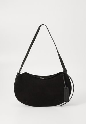 Black suede shoulder bag with a curved shape, adjustable strap, and a leather tag hanging from one side.