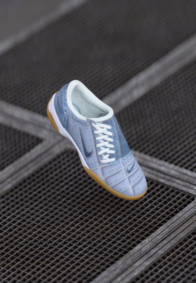 Světle modré denimové tenisky s bílými tkaničkami a tmavě modrými akcenty, s kulatou špičkou a gumovou podrážkou. Texturovaný povrch s detaily šití.