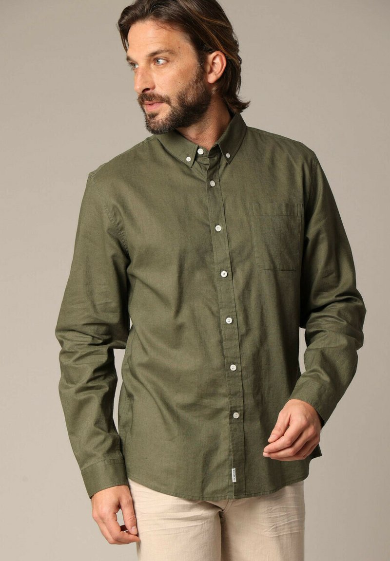 Olijfgroene button-up shirt van een zachte stof met lange mouwen, een borstzak en witte knopen. Het heeft een klassieke kraag en een recht model.