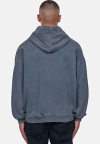 Kapütsiga sweatshirt pleekinud hallist kangast, millel on mugav lõige, soonikkoes mansetid ja vöökoht, ning lihtne, kaunistusteta disain.