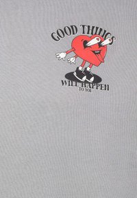 Gray cotton t-shirt featuring a red heart character with cartoonish eyes, arms, and legs, accompanied by black text: "GOOD THINGS WILL HAPPEN TO YOU."