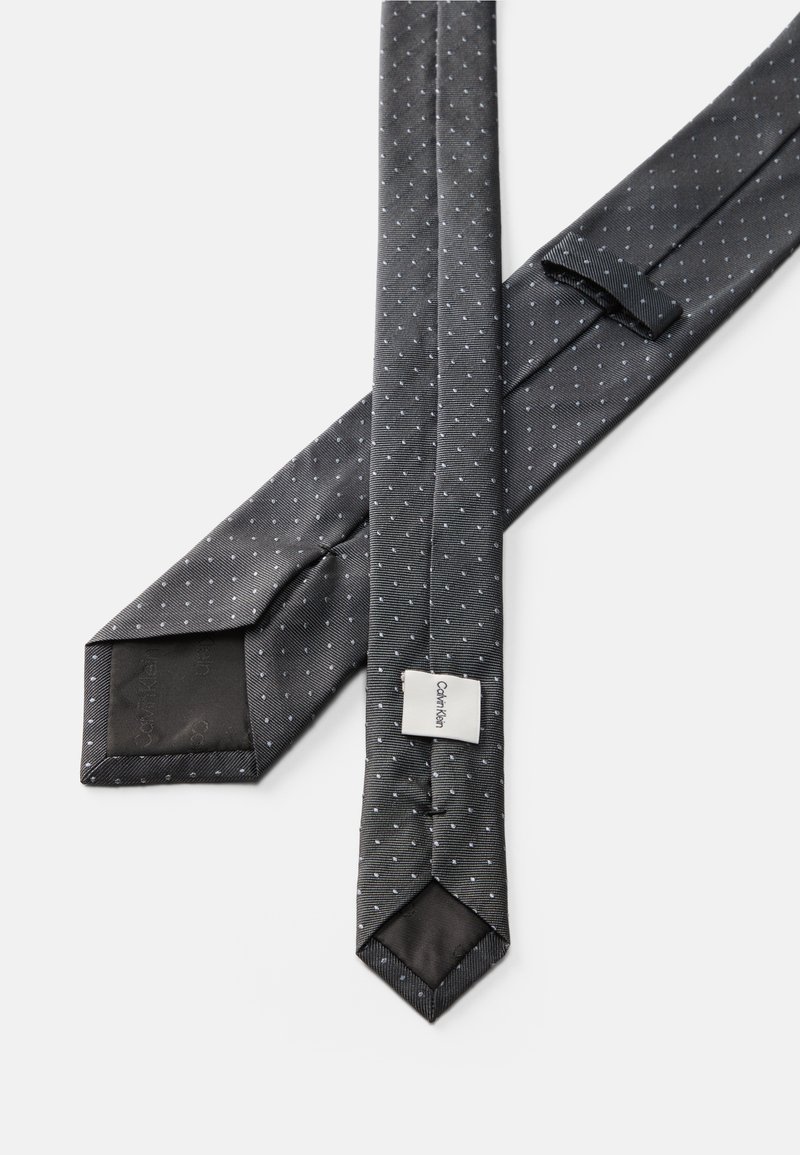 Zwart stropdas met kleine witte stippen. Gemaakt van textuurstof, met een spitse punt en een label. Glad afgewerkt aan de achterzijde.