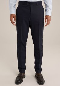 Marineblauwe pantalon met een getailleerde pasvorm, voorzien van een subtiele textuur, rechte pijpen en een platte voorkant, gecombineerd met donkere instappers.