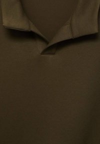 Polo shirt verde oliva con una texture morbida, caratterizzato da un colletto a V e colletto pieghevole. Design semplice, senza motivi o accessori visibili.